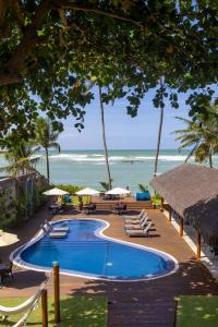 einen Pool am Strand mit Stühlen und Sonnenschirmen in der Unterkunft Flor de Lis Exclusive Hotel in Maceió