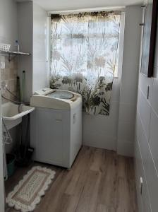 a bathroom with a washing machine and a window at Apto praia pontal, vista mar in Rio de Janeiro