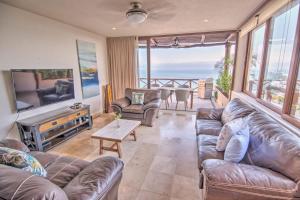 una sala de estar con muebles de cuero y vistas al océano. en Punta Esmeralda - Beachfront with 8 Pools, Gym & Spa, en Cruz de Huanacaxtle