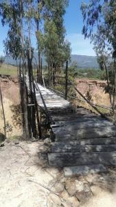 un puente colgante sobre un camino de tierra con árboles en La madriguera de Guatavita, en Guatavita