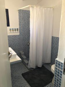 a bathroom with a shower with a white shower curtain at Mini Villas Blue in Keratokampos