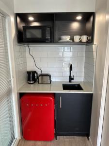 Il comprend une petite cuisine équipée d'un four micro-ondes et d'un réfrigérateur rouge. dans l'établissement 66 Express luxury apartment in New Market Our apartments has Self-checkin System, à Auckland