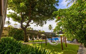 a group of hammocks in a yard with a pool at Flor de Lis Exclusive Hotel in Maceió