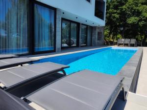 uma piscina com duas espreguiçadeiras ao lado de uma casa em Villa Lapidea em Sinj
