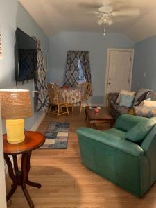 ein Wohnzimmer mit einer grünen Couch und einem Tisch in der Unterkunft Pink Flamingo at the Beach cottage in North Camellia Acres
