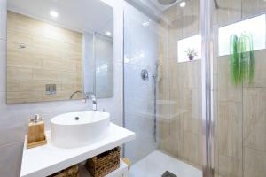La salle de bains est pourvue d'un lavabo blanc et d'une douche. dans l'établissement COZY BOHO HOUSE, Elegance & Comfort in Faro Center, à Faro