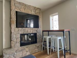 salon z kamiennym kominkiem i telewizorem z płaskim ekranem w obiekcie Frostwood w mieście Mount Buller