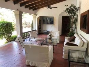 a living room with white furniture and a tv at Casa La Bonita in Cuernavaca