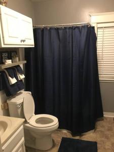 a bathroom with a toilet and a black shower curtain at Home Away in Erie
