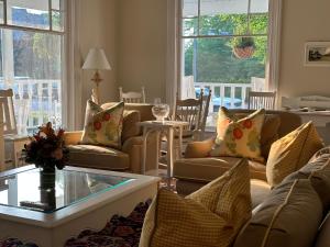 uma sala de estar com sofás, uma mesa e janelas em The Belvedere B&B em Charlevoix