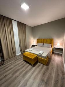 - une chambre avec un grand lit et une planche de pied jaune dans l'établissement Bejart Apartment 4, à Tirana