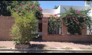 un bâtiment en briques avec deux buissons aux fleurs roses dans l'établissement LA MAMA, à Mercedes