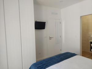 una camera da letto con un letto e una TV a parete di Lagoa azul guest house II a Vila Nova de Milfontes