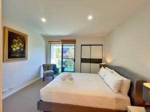um quarto com uma grande cama branca e uma cadeira em Phillip Island Towers em Cowes