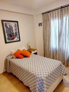 1 dormitorio con 1 cama con almohadas de color naranja y ventana en DEPARTAMENTO CENTRICO en Santa Rosa