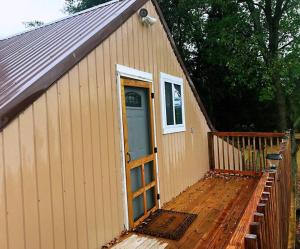 ein kleines Haus mit einer Tür und einer Holzterrasse in der Unterkunft Eden Farm: Private Studio Minutes from Salisbury in Eden