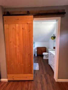 a bathroom with a toilet and a wooden door at Eden Farm: Private Studio Minutes from Salisbury in Eden