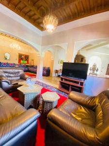 sala de estar con muebles de cuero y TV de pantalla plana en Villa ELIANA, en Marrakech