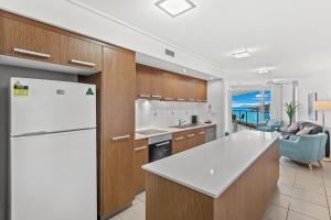 a kitchen with a white refrigerator and a dining room at Serenity Views in Airlie Beach