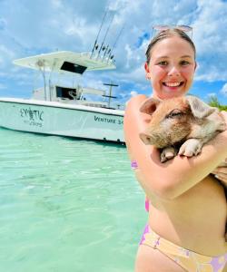 Eine Frau im Bikini, die einen Koala vor einem Boot hält. in der Unterkunft Boathouse La Bougainvillea cottage in Governors Harbour