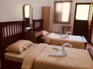 dois cisnes estão sentados em duas camas num quarto em Tatay Seseng's Apartment em Panglao