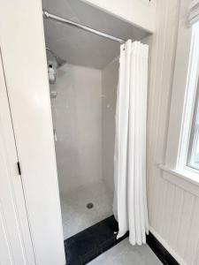 ein Bad mit Dusche und Duschvorhang in der Unterkunft Cottage Retreat - Historic Cottage Home w Home Gym 