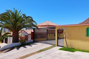 a black gate in front of a house with a palm tree at Cabañas Las Flores - Barrio residencial La Herradura in Coquimbo