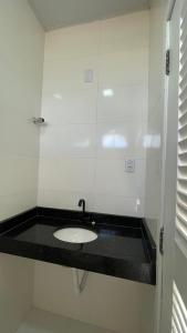 La salle de bains est pourvue d'un lavabo et d'un comptoir noir. dans l'établissement Apartamento no Atalaia, à Salinópolis