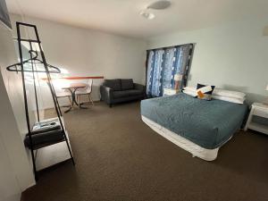 a bedroom with a bed and a chair and a ladder at Alpine View Motel in Kaikoura