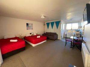 a bedroom with two beds and a table and a chair at Alpine View Motel in Kaikoura