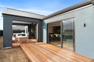 a house with a deck with sliding glass doors at CatchN'Relax Taupo in Taupo