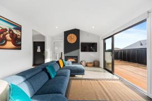 a living room with a blue couch and a fireplace at CatchN'Relax Taupo in Taupo