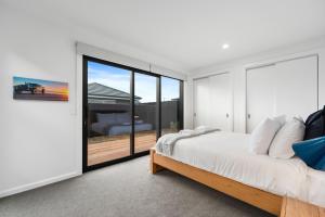 a bedroom with a bed and a sliding glass door at CatchN'Relax Taupo in Taupo