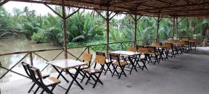 eine Reihe von Tischen und Stühlen mit Bäumen im Hintergrund in der Unterkunft Traveler’s choice home in Vietnam 1 in Củ Chi