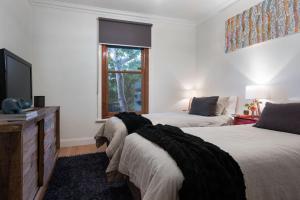 a bedroom with two beds and a tv and a window at Absolute in Daylesford
