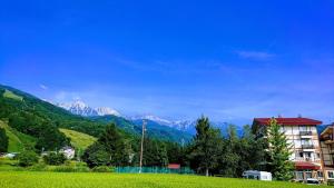 a building on a hill with mountains in the background at Rosenheim Hakuba in Hakuba