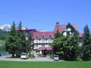 a large house with a clock on the front of it at Rosenheim Hakuba in Hakuba