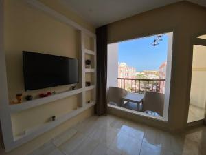 a living room with a flat screen tv and a large window at ديزرت بيرل in Hurghada
