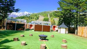 a garden with a table and stumps in the grass at Rosenheim Hakuba in Hakuba