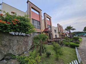 um edifício com plantas ao lado dele em Red Castle Pension em Jeju