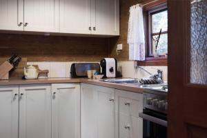 uma cozinha com armários brancos e um lavatório em All Views em Daylesford