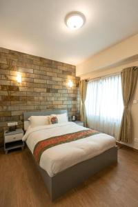 a bedroom with a large bed and a brick wall at Pata Inn in Kathmandu