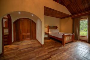 a bedroom with a bed and a wooden floor at Arenal ginger home in Fortuna