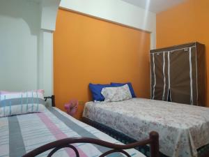 1 dormitorio con 2 camas y pared de color naranja en Suite Magy-Manta, en Manta