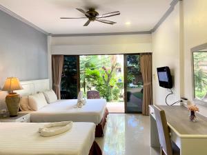 a hotel room with two beds and a tv at Garden Home Kata in Kata Beach