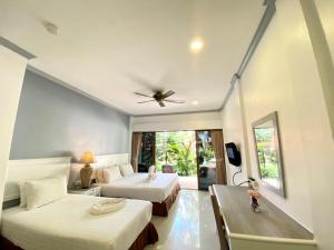 a hotel room with two beds and a ceiling fan at Garden Home Kata in Kata Beach