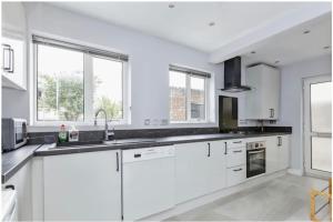 una cocina blanca con armarios blancos y ventanas en 3 Bedroom House in Loughborough en Loughborough