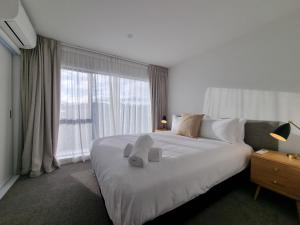 a bedroom with a white bed with a large window at Alpine Junction Townhouse Apartments, Lodge & Hotel in Wanaka