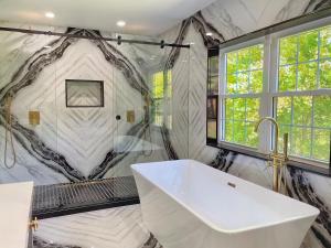 La salle de bains est pourvue d'une baignoire blanche et d'une fenêtre. dans l'établissement Estate Getaway, à Glen Cove