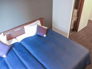 a bedroom with two beds with blue sheets and pillows at HOTEL LiVEMAX Chiba Minato Eki-mae in Chiba